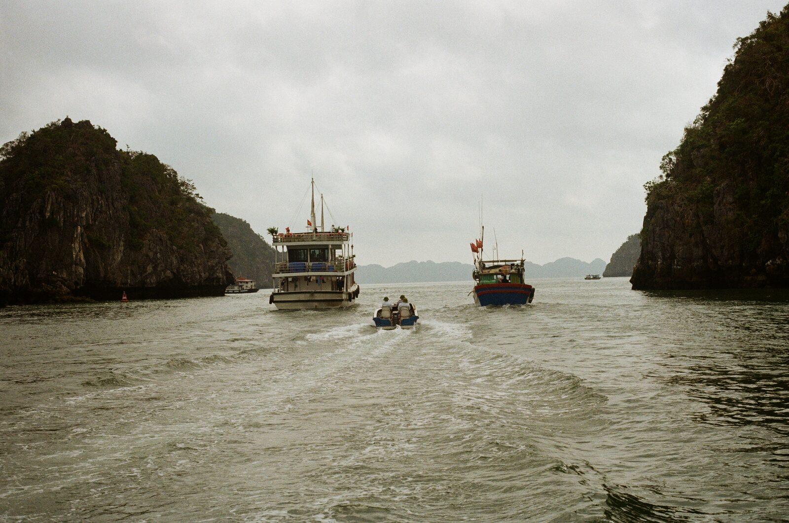 Tour boats passing between limestone islands in Ha Long Bay