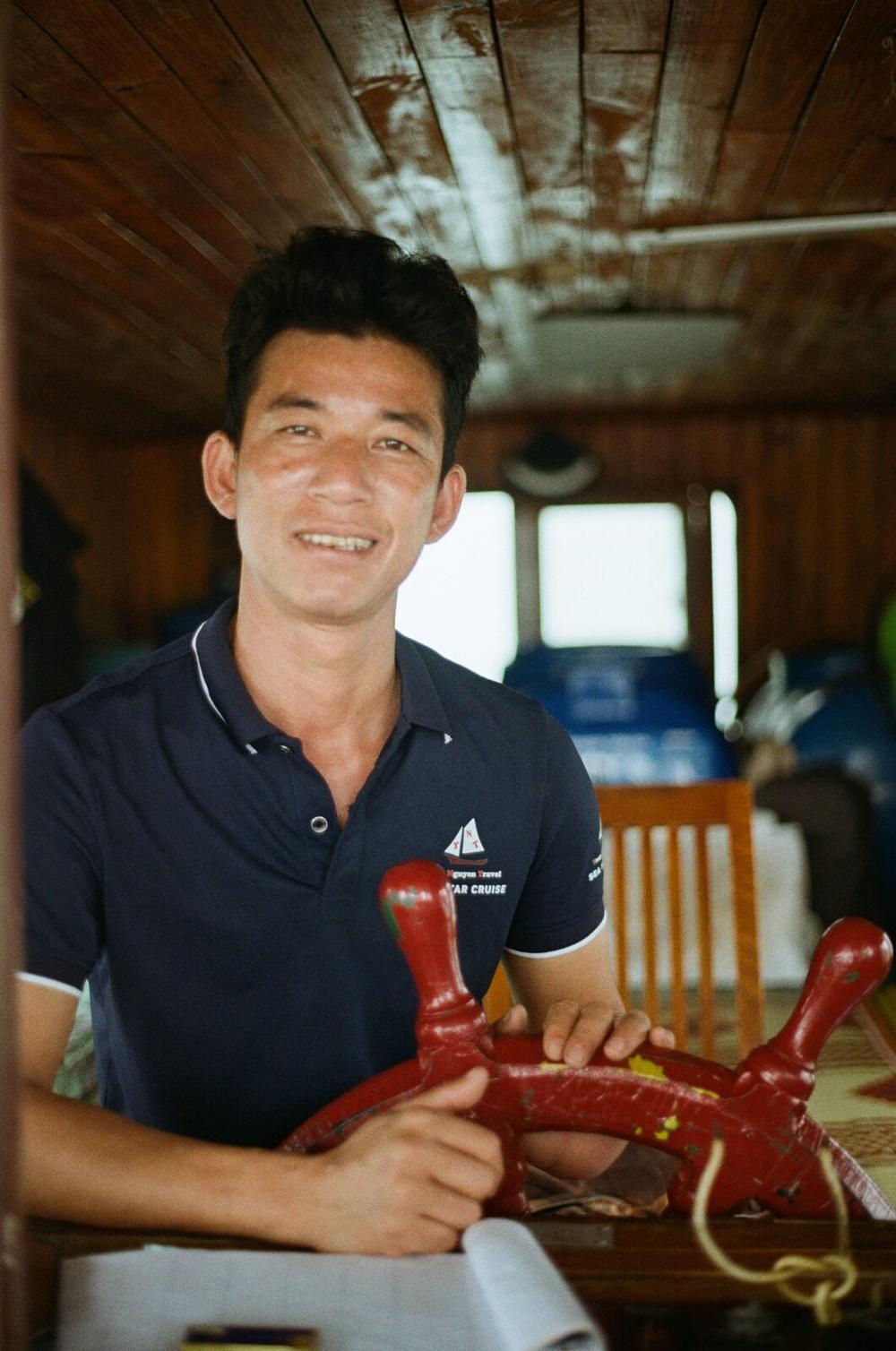 A boat crew member smiling at the wheel of a cruise boat