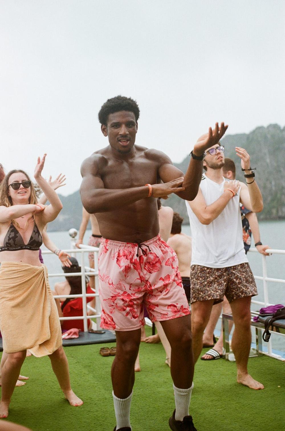 A man dancing on the deck of a boat with other passengers